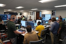 people standing and sitting looking at computer screens