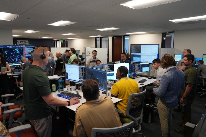 people standing and sitting looking at computer screens