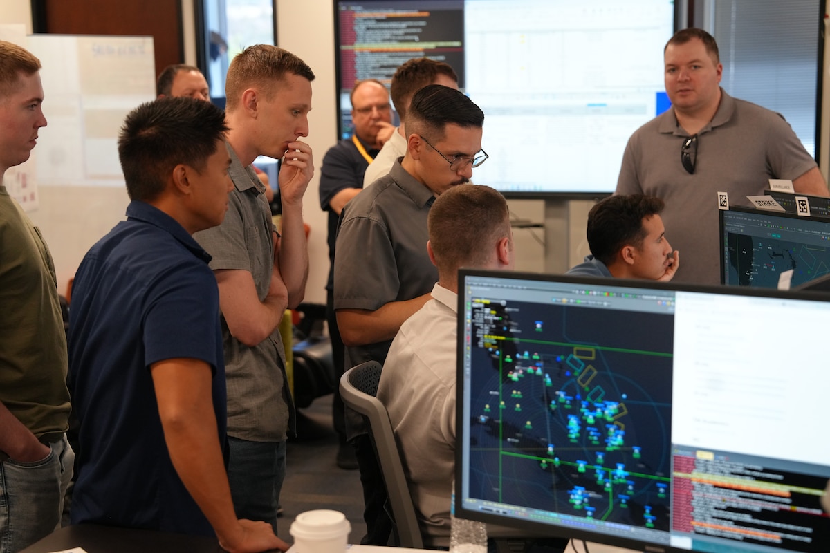 people standing and sitting looking at computer screens