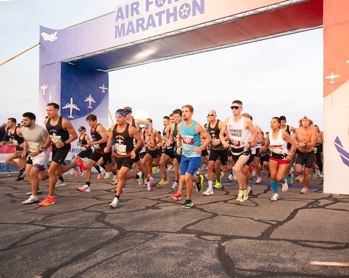 Competitors run under an arch that says "Air Force Marathon"