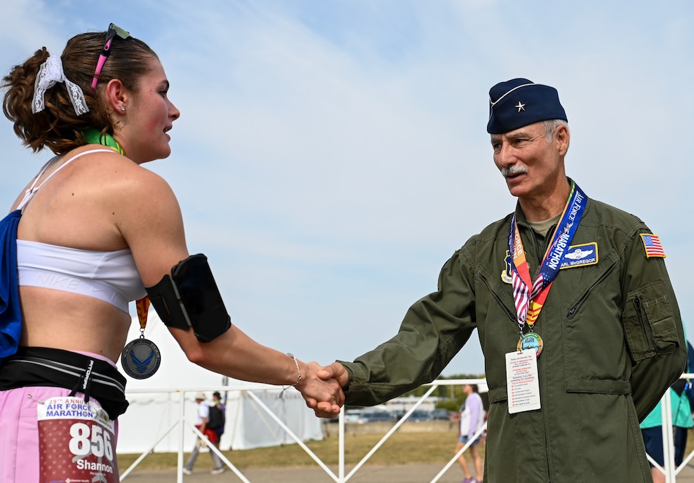 Retired U.S. Air Force Brig. Gen. Karl McGregor, right, congratulates a participant of the 29th annual Air Force Marathon at Wright-Patterson Air Force Base, Ohio, Sept. 20, 2025. As part of Operation Honor 2025, veterans were on hand to cheer on runners and present medals to winners while also engaging with younger generations of service members before tomorrow's historic Honor Flight on an Air Force Reserve C-17 Globemaster III assigned to the 445th Airlift Wing. (U.S. Air Force photo by Staff Sgt. Johnathan Quiñones)