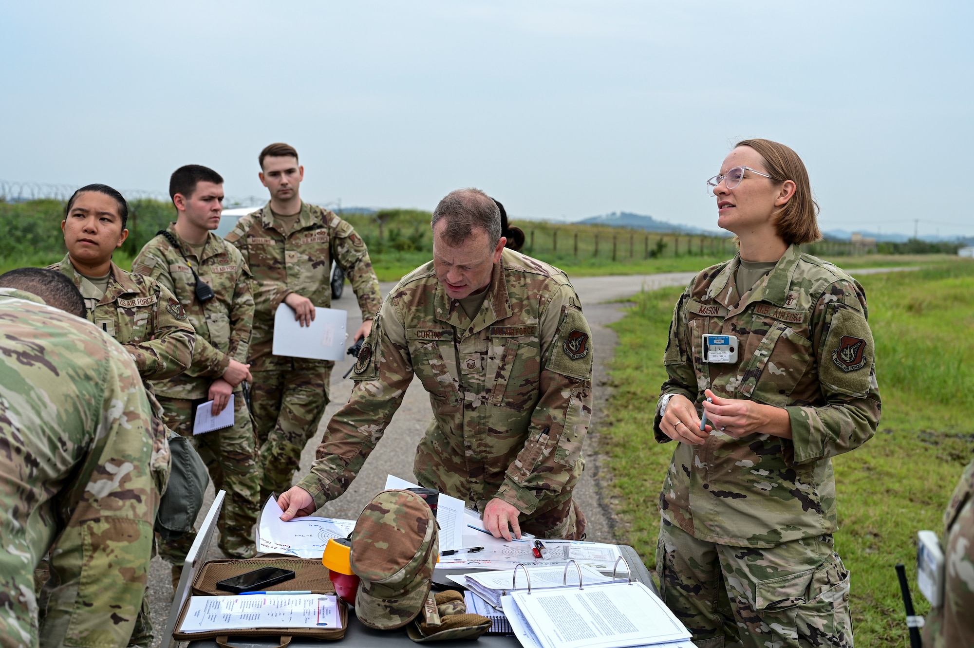 A group of people study plans on a table.
