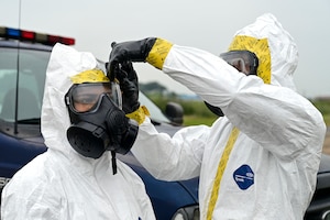 A man applies tape to a womans gas mask.