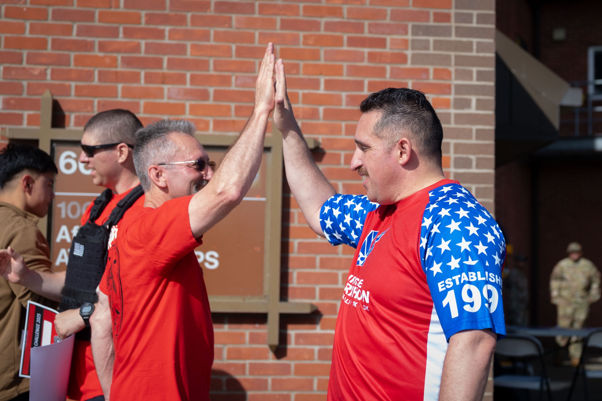 U.S. Air Force Master Sgt. Jose Arriaga (right), 100th Civil Engineer Squadron engineering superintendent, and Mr. Mitchell Costa, 100th Civil Engineer Squadron deputy base civil engineer, high-five at the bottom of the air traffic control tower during the 9/11 Memorial Climb at RAF Mildenhall, England, Sept. 11, 2025.