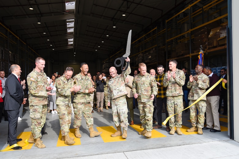 row of officers clapping. one man holds up a giant pair of scissors.