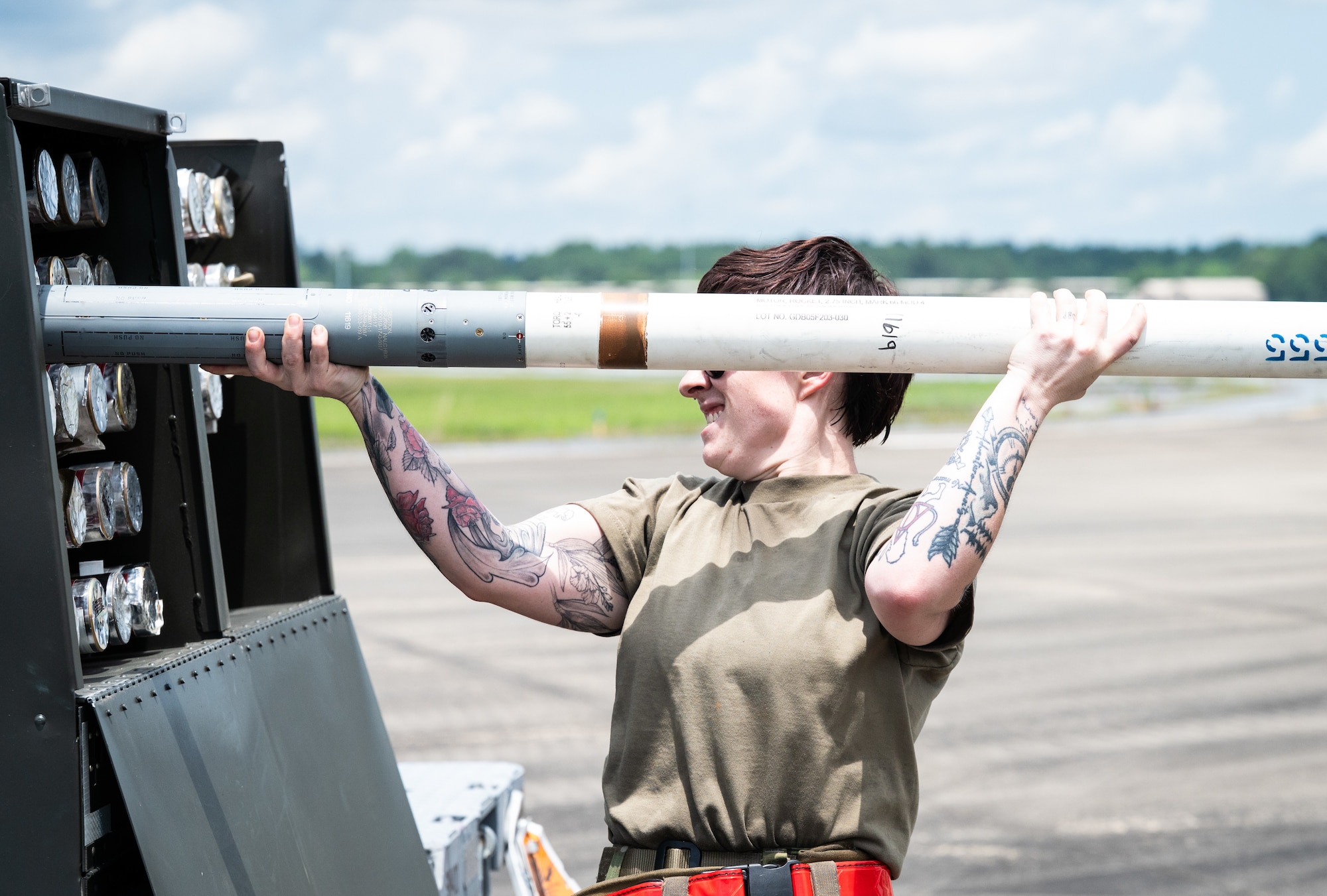 A female maintainer  pulls a rocket out of its case