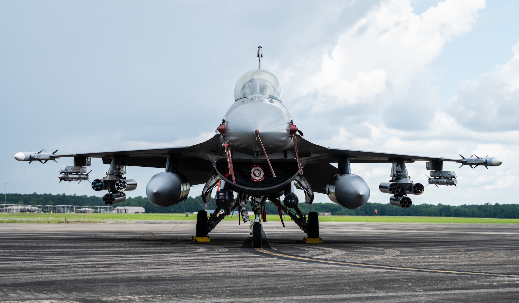An Air Force F-16 sits on a flightline with fully loaded munitions