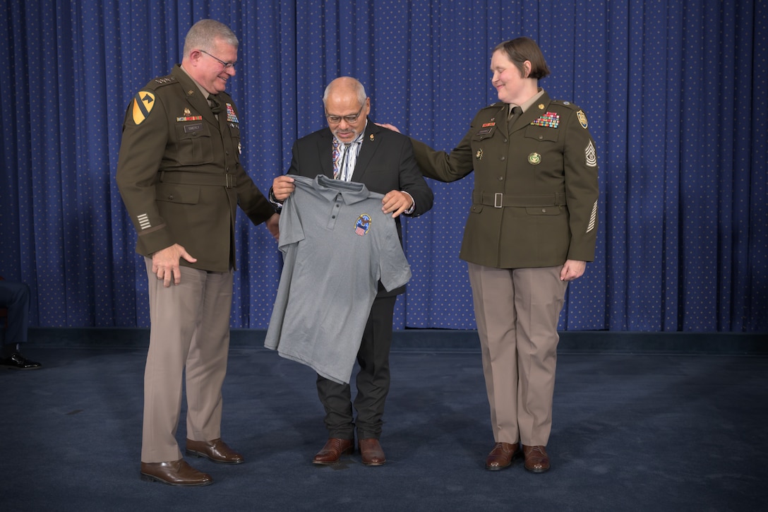 A man receives a gray shirt with the Defense Logistics Agency's logo on it from the agency's director.