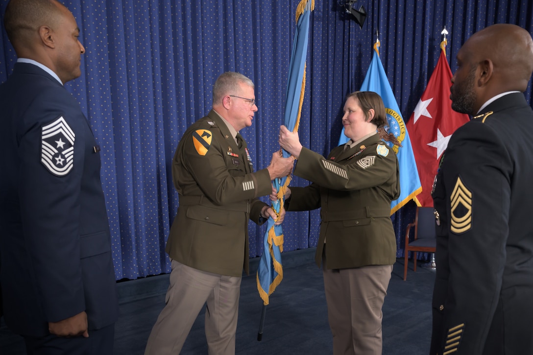 A three-star Army general hands a flag to a command sergeant major.