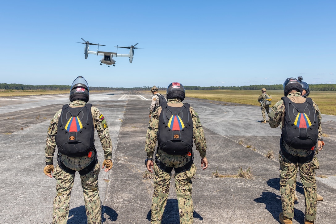 Marines with Cuerpo de Infantería de Marina (Ecuadorian marines) watch as an MV-22B Osprey tiltrotor aircraft, assigned to Marine Medium Tiltrotor Squadron (VMM) 261 lands at the staging area to conduct sustainment jumps during exercise UNITAS 2025 at Marine Corps Base Camp Lejeune, North Carolina, Sept. 20, 2025. UNITAS, which is Latin for “unity,” was conceived in 1959 and has taken place annually since first conducted in 1960. This year marks the 66th iteration of the world’s longest running annual multinational maritime exercise. (U.S. Marine Corps photo by Lance Cpl. Payton Goodrich)