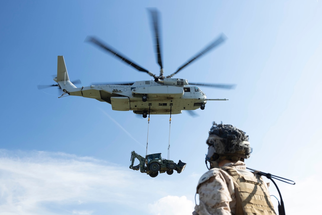 U.S. Marine Corps Sgt. Damion Silva, from Montana, a logistics specialist with Combat Logistics Battalion 22, Combat Logistics Regiment 27, 2nd Marine Logistics Group, watches a CH-53K King Stallion aircraft lift a 420E backhoe loader during exercise UNITAS 2025 at Marine Corps Air Station New River, North Carolina, Sept. 18, 2025. UNITAS, which is Latin for “unity,” was conceived in 1959 and has taken place annually since first conducted in 1960. This marks the 66th iteration of the world’s longest running annual multinational maritime exercise. (U.S. Marine Corps photo by Cpl. Mya Seymour)