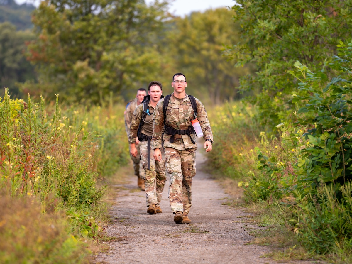 Airmen ruck down a path.