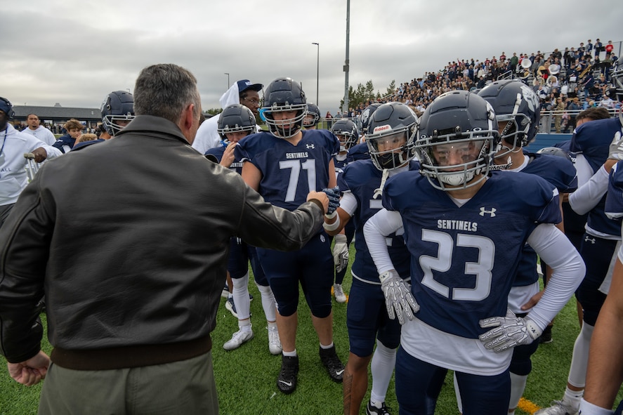Col. Jesse Lamarand, 5th Bomb Wing commander, fist bumps a Minot North High School football player before the homecoming game at Minot, North Dakota, Sept. 20, 2025. Leadership from the 5th BW and 91st Missile Wing took part in pre-game activities to honor the community and kick off the game. (U.S. Air Force photo by Senior Airman Luis Gomez)