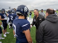 Col. Jesse Lamarand, 5th Bomb Wing commander, shakes hands with a Minot North High School football player prior to the homecoming game at Minot, North Dakota, Sept. 20, 2025. Leaders from the 5th BW and 91st Missile Wing participated in pre-game ceremonies to deliver the game ball. (U.S. Air Force photo by Senior Airman Luis Gomez)