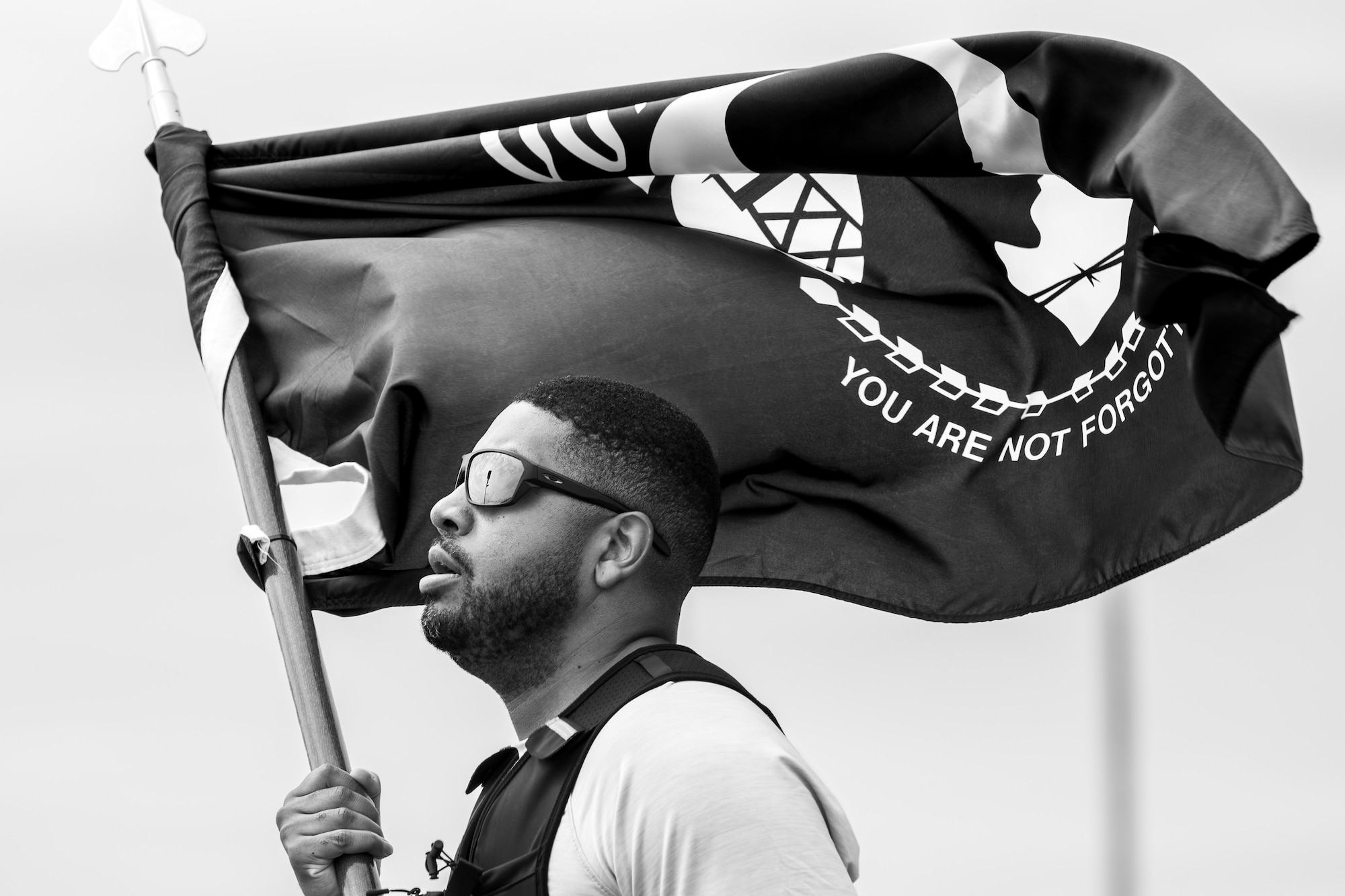 Airman runs around track with flag.