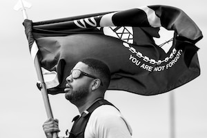 Airman runs around track with flag.