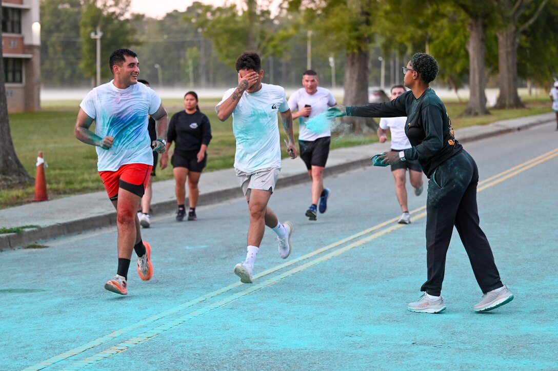 Soldier douses runners with colored powder.