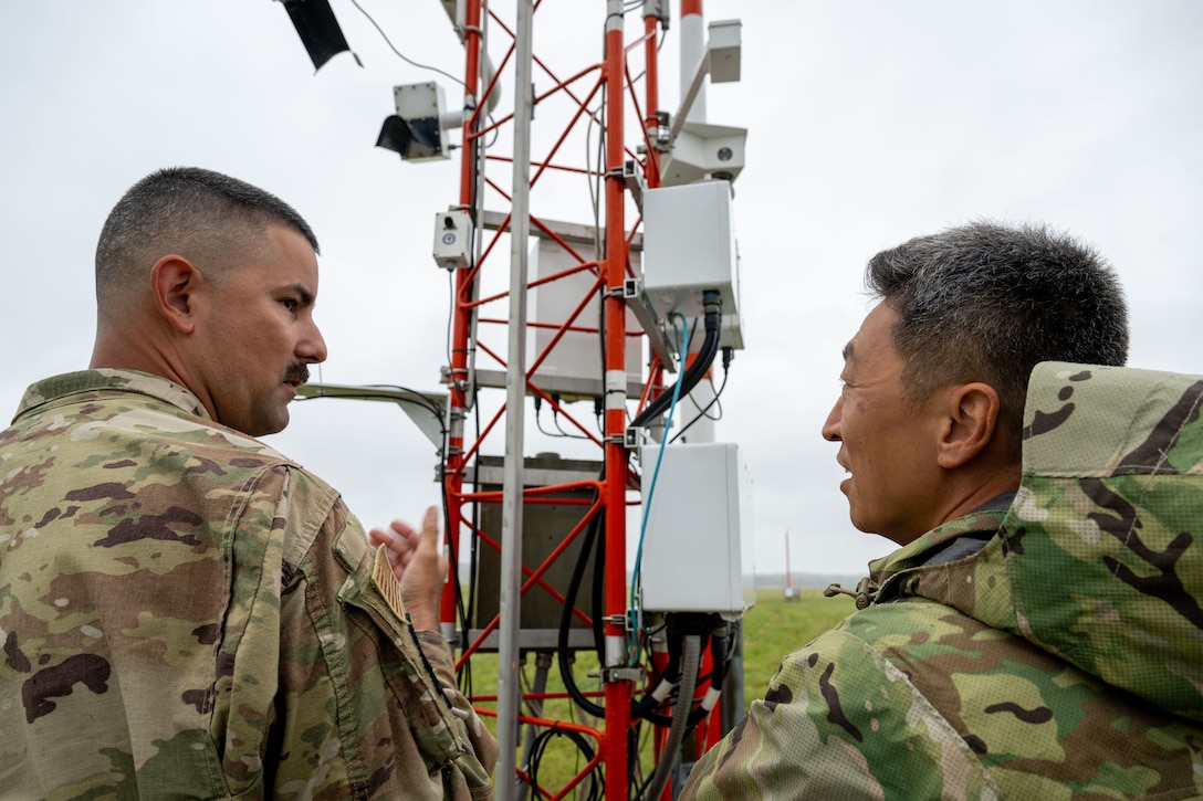 U.S. Air Force Senior Airman Andrew Caballero, 316th Operations Support Squadron radar, airfield and weather systems journeyman, and Col. Jun S. Oh, 316th Wing and installation commander, discuss mission tasks on the airfield at Joint Base Andrews, Maryland, Sept. 17, 2025. The weather suite is part of the RAWS operation, which ensures that all radar, weather equipment, fixed and deployable navigational aids, and communications systems are maintained and operational to keep aircraft safe during takeoff, flight and landing.