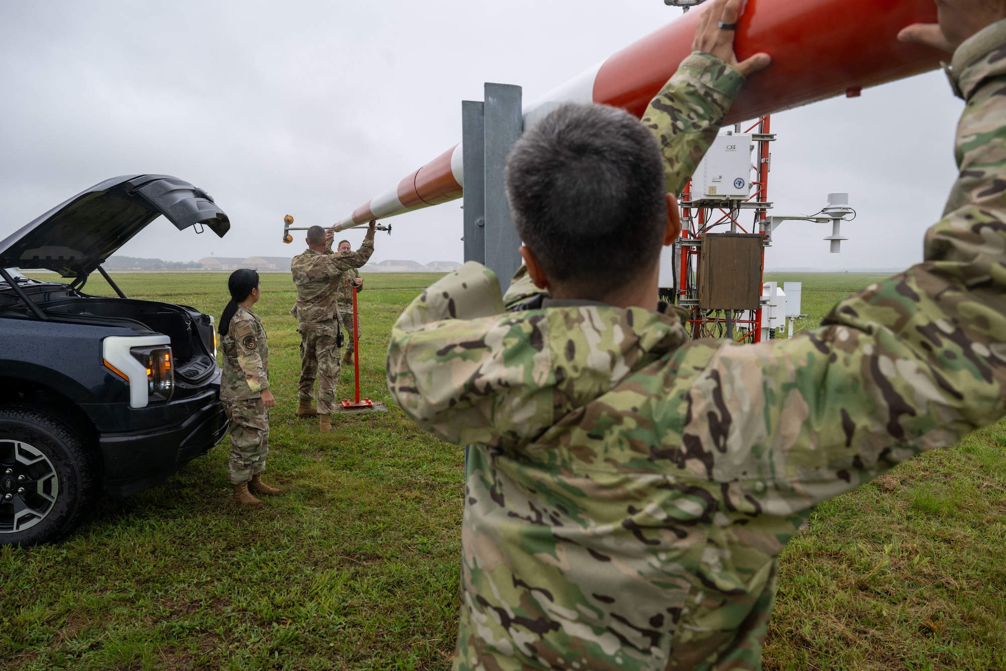 U.S. Air Force Senior Airman Andrew Caballero, 316th Operations Support Squadron radar, airfield and weather systems journeyman, Col. Jun S. Oh, 316th Wing and installation commander, and Chief Master Sgt. Kevin Helms, 316th Wing command chief, tilt the wind mass at Joint Base Andrews, Maryland, Sept. 17, 2025. The wind mass has a wind sensor that needs to be changed periodically to ensure safety.
