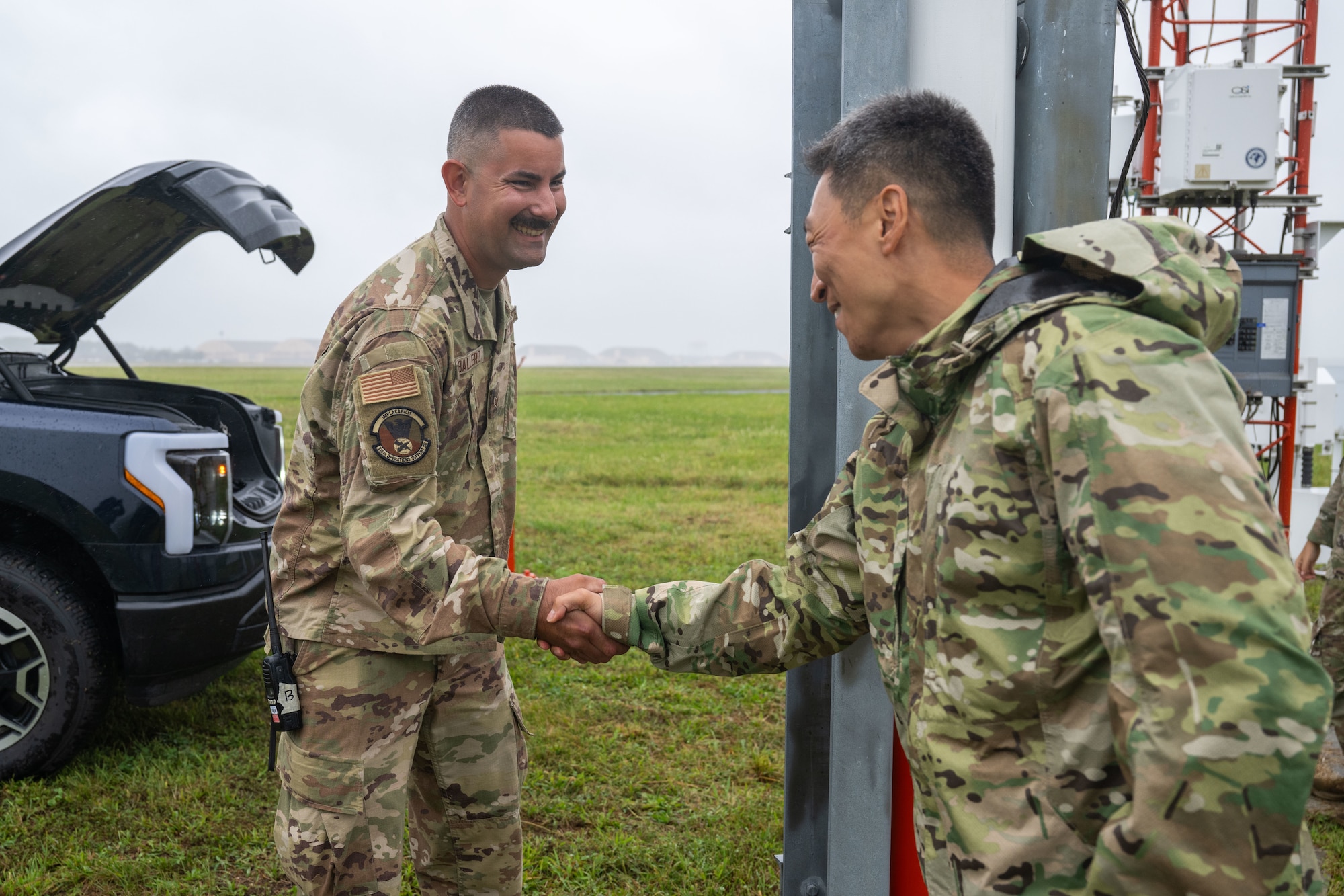 U.S. Air Force Senior Airman Andrew Caballero, 316th Operations Support Squadron radar, airfield and weather systems journeyman, and Col. Jun S. Oh, 316th Wing and installation commander, shake hands after recognizing Caballero for superior performance at his job at Joint Base Andrews, Maryland, Sept. 17, 2025. Caballero explained the importance of the FMQ-19 and provided a hands-on demonstration of taking down the wind sensor tower and putting it back up.