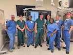 A vascular surgery team poses in an operating room at Walter Reed National Military Medical Center after completing a thoracoabdominal branch endoprosthesis (TAMBE) procedure. It was the first time Walter Reed performed this procedure, making the hospital one of only three in the region qualified to do so.