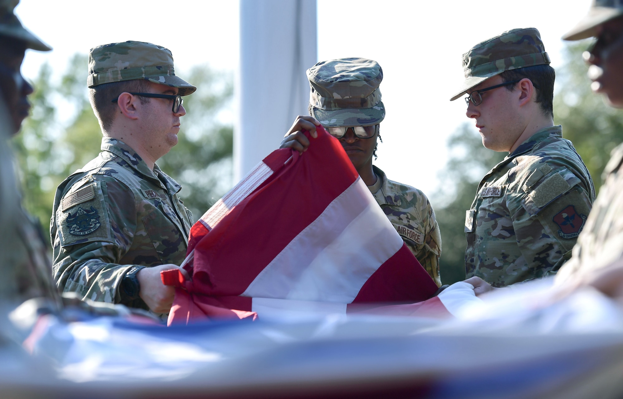A group of people in military uniform fold a U.S. flag
