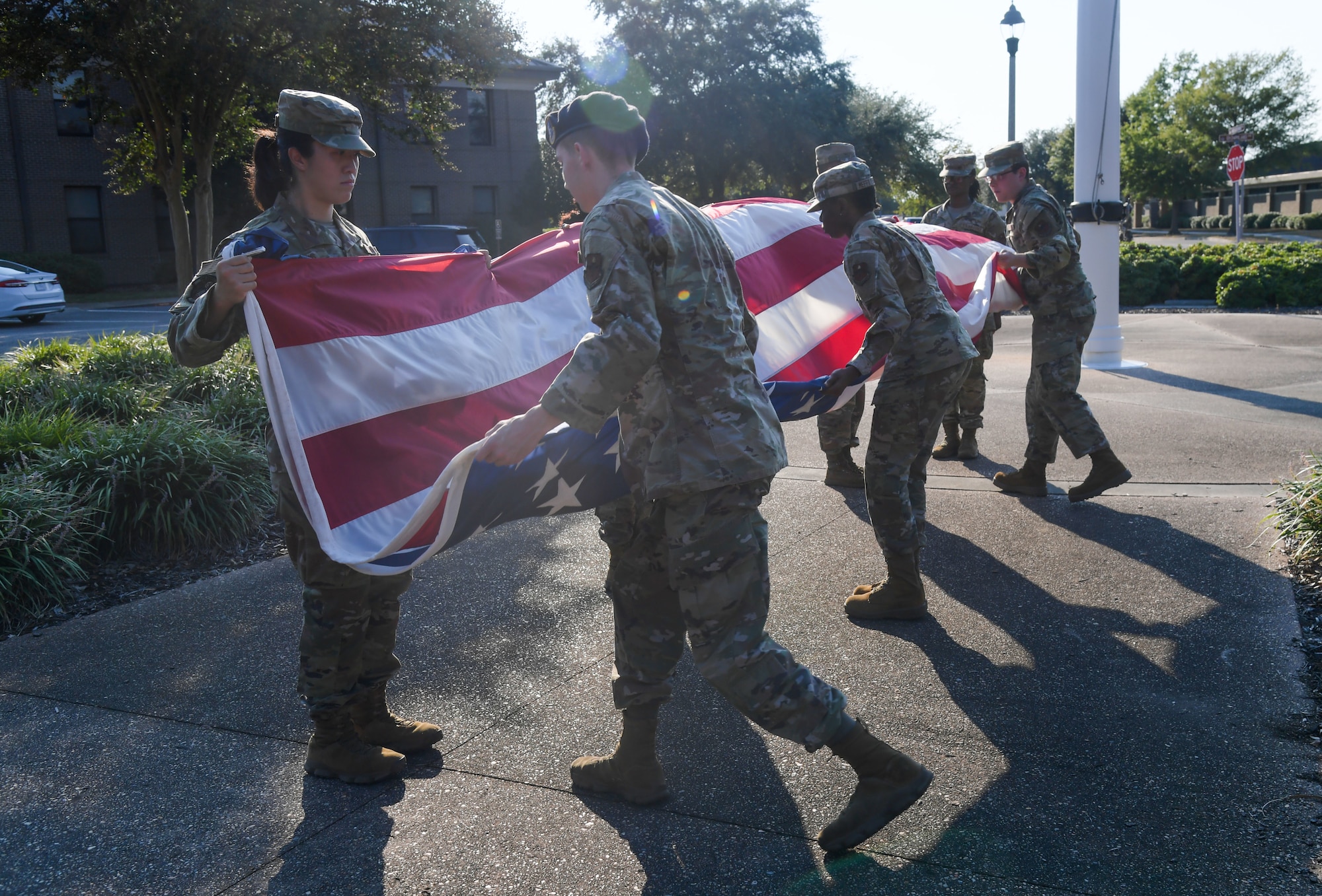 A group of people in military uniform fold a U.S. flag