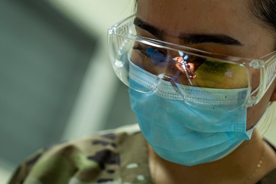 A U.S. Air Force member looks down while wearing a facemask and protective classes.
