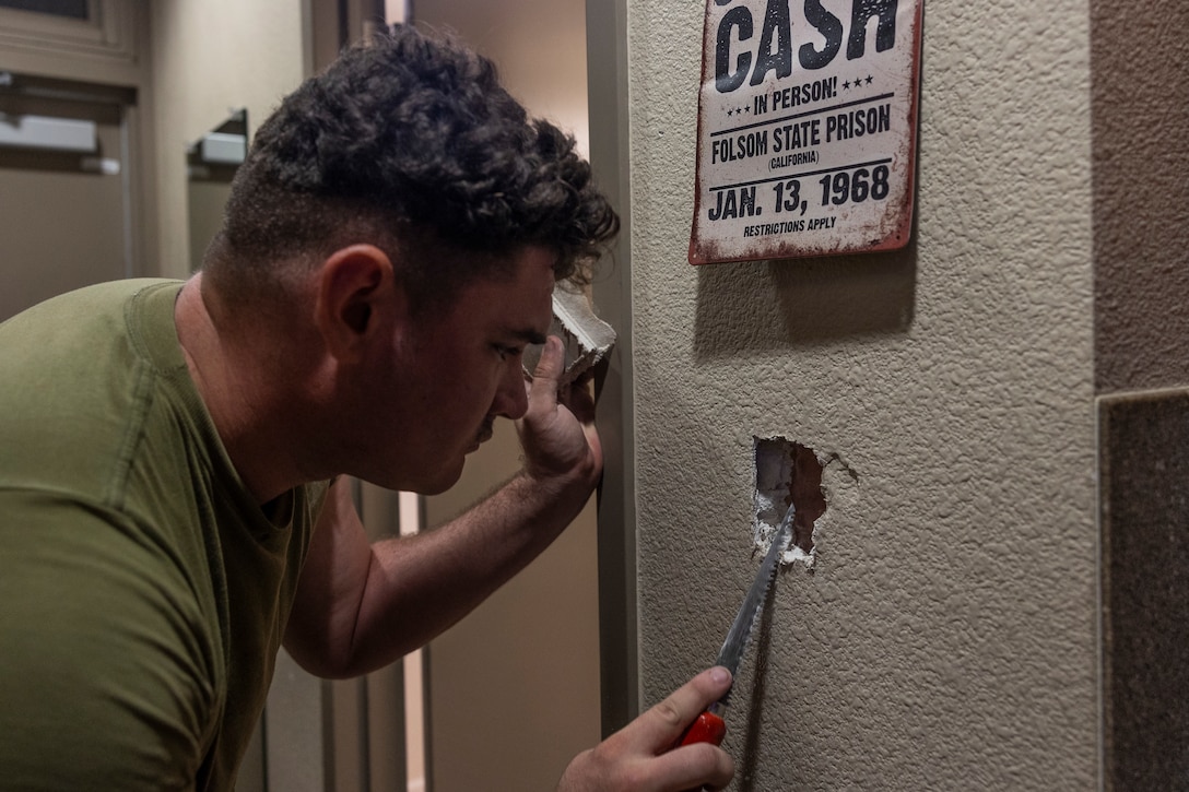 U.S. Marine Corps Lance Cpl. Andrew Rivers, an automotive maintenance technician with I Marine Expeditionary Force Support Battalion, I Marine Expeditionary Force, resizes a hole to fit dry wall during Operation Clean Sweep III at Marine Corps Base Camp Pendleton, California, Sept. 19, 2025.