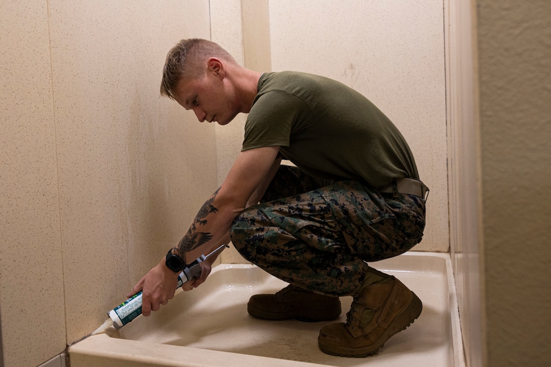 U.S. Marine Corps Lance Cpl. Daniel Torkelson, an infantry weapons repairer with I Marine Expeditionary Force Support Battalion, I Marine Expeditionary Force, applies caulk to a shower wall during Operation Clean Sweep III at Marine Corps Base Camp Pendleton, California, Sept. 19, 2025.