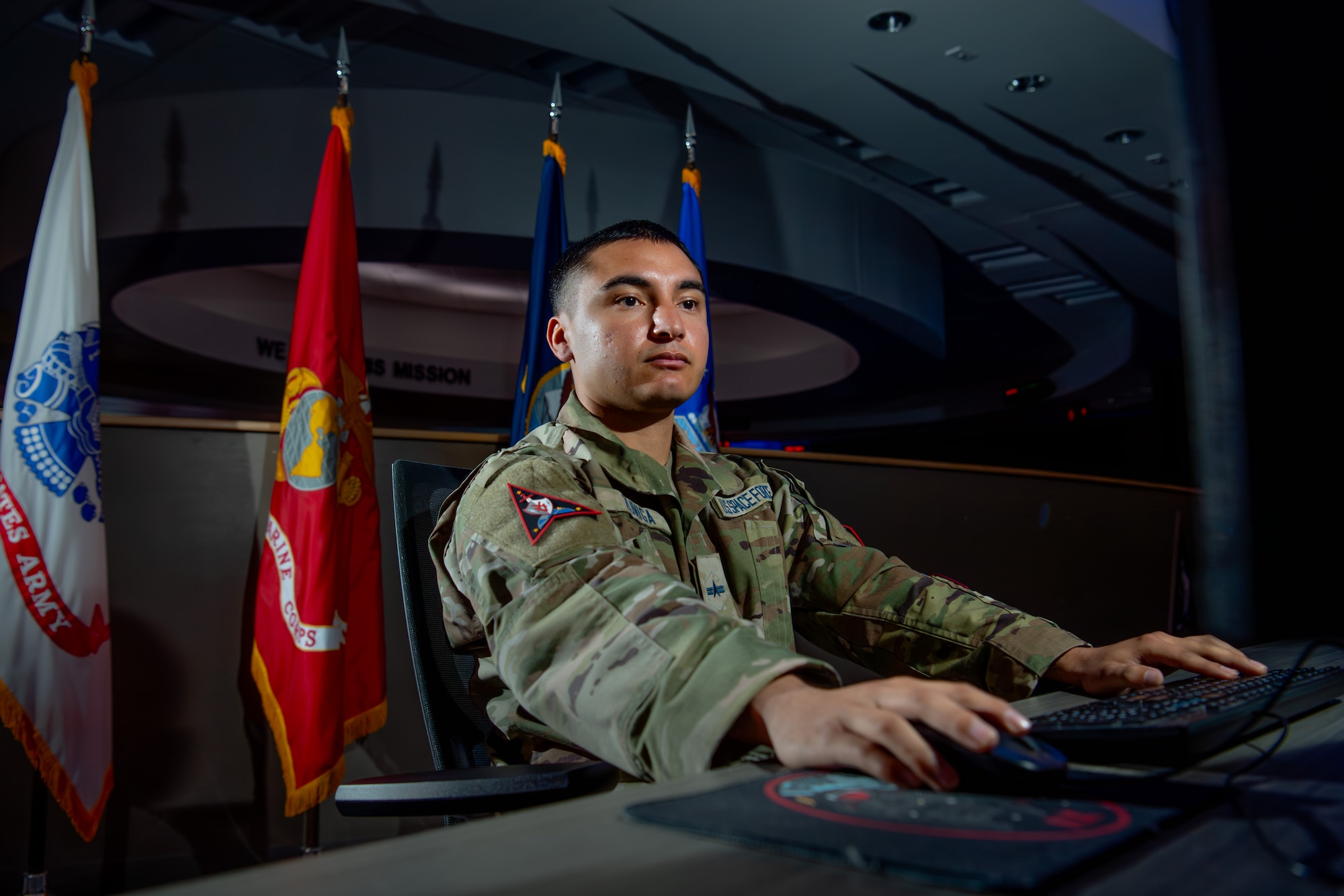 A man in a military uniform works on his computer in an operations center