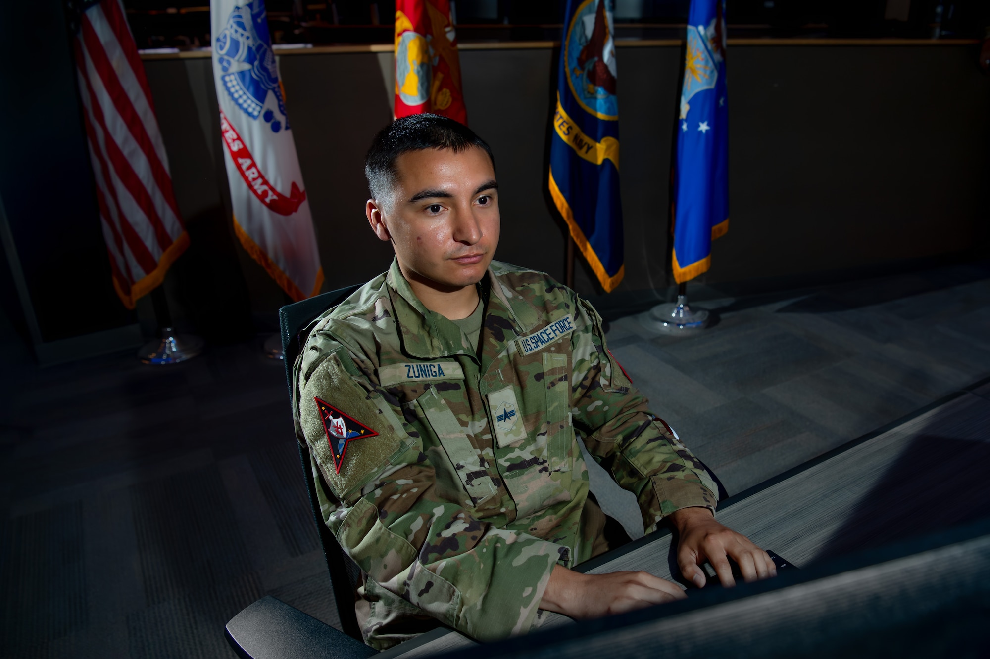 A man in uniform works on his computer in an operations center