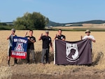 From left to right, Max von Husen, Zachariah Ellwanger, Lt. Col. Rich Ingleby, Carson Criswell, and Jonathan Ellwanger from the University of Arizona pose with their university flag, and the POW/MIA flag in Poland, Aug. 9, 2025.