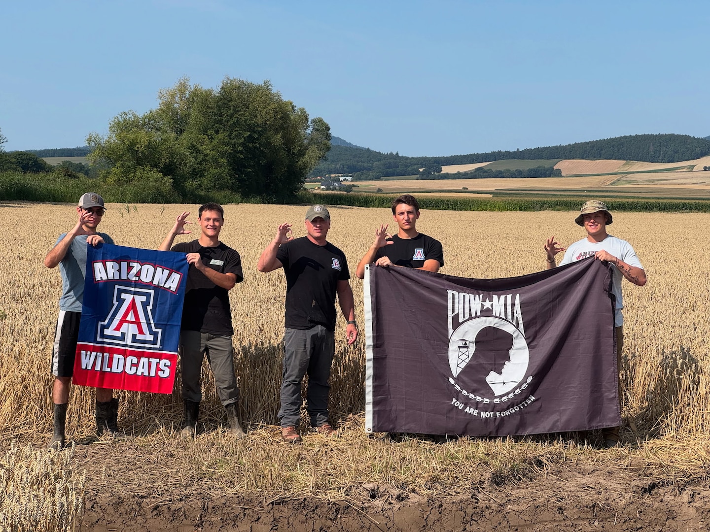 From left to right, Max von Husen, Zachariah Ellwanger, Lt. Col. Rich Ingleby, Carson Criswell, and Jonathan Ellwanger from the University of Arizona pose with their university flag, and the POW/MIA flag in Poland, Aug. 9, 2025.