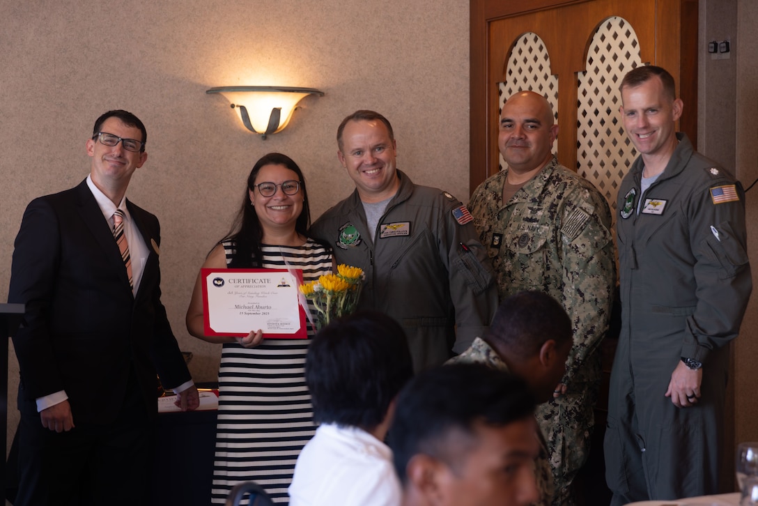 Michael Aburto, center left, an ombudsman with U.S. Navy Strike Fighter Attack Squadron (VFA) 195, Carrier Air Wing 5, U.S. Pacific Fleet, poses for a photo after receiving a certificate of appreciation during a lunch celebrating the 55th anniversary of the Navy Family Ombudsmen Program at Marine Corps Air Station Iwakuni, Japan, Sept. 15, 2025. Ombudsmen serve as volunteer liaisons between the command and families, helping with resources, mission readiness and family welfare. (U.S. Marine Corps photo by Lance Cpl. Ella Cadby)