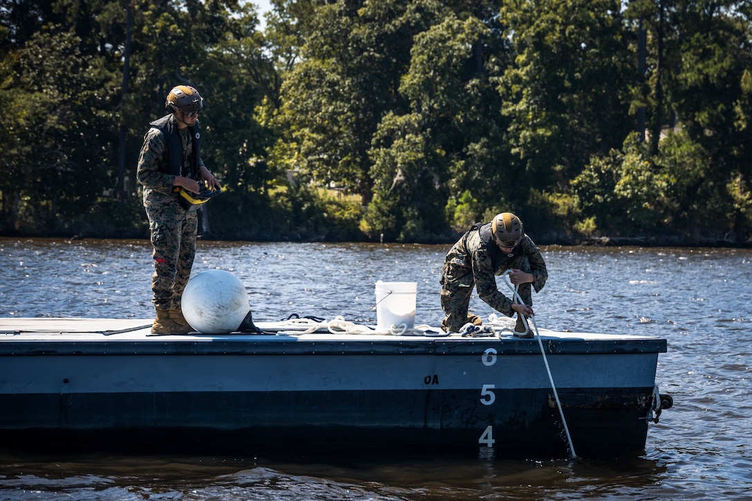 U.S. Marine Corps Lance Cpl. Andrew Nugent, left, a motor vehicle operator with Maritime Distribution Platoon, 2nd Distribution Support Battalion, Combat Logistics Regiment 2, drives an autonomous low-profile vessel while Lance Cpl. Ian Sossoman, a motor vehicle operator with Maritime Distribution Platoon, 2nd DSB, CLR 2, retrieves an anchor in preparation for exercise UNITAS 2025 at Marine Corps Base Camp Lejeune, North Carolina, Sept. 17, 2025. 2nd Marine Logistics Group is working with the Marine Corps Warfighting Lab to experiment with the ALPV for a more lethal, agile, and resilient capability while conducting expeditionary advanced base operations. UNITAS, which is Latin for “unity,” was conceived in 1959 and has taken place annually since first conducted in 1960. This year marks the 66th iteration of the world’s longest running annual multinational maritime exercise. The exercise trains forces in joint maritime operations that enhance tactical proficiency and increase interoperability with the presence of unmanned air, surface and submarine systems. Nugent is a native of Connecticut. Sossoman is a native of Florida. (U.S. Marine Corps photo Rafael Brambila-Pelayo)