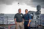 From left, Aviation Machinist's Mate Senior Chief Dan Reyes and his daughter, U.S. Midshipmen 2nd Class Gabriella Reyes, from Miami, Florida, pose for a photo during a vertical replenishment on the fantail aboard the aircraft carrier USS Nimitz (CVN 68) in the South China Sea, June 10, 2025. Nimitz is underway in the U.S. 7th Fleet area of operations on a scheduled deployment, demonstrating the U.S. Navy's unwavering commitment to a free and open Indo-Pacific.