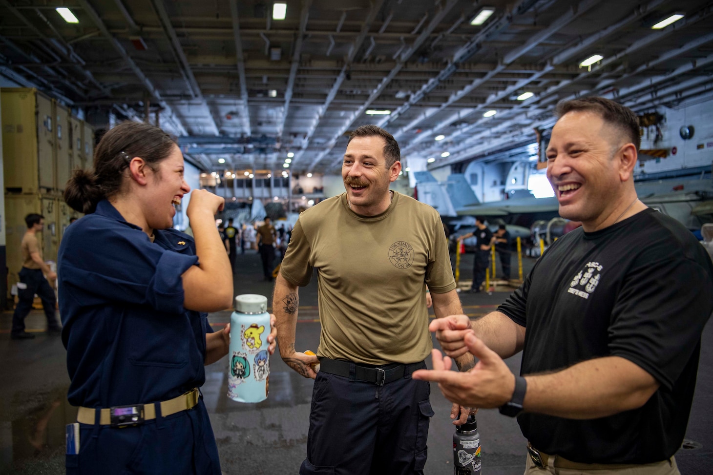 Senior Chief Aviation Machinist's Mate Dan Reyes, left, and his daughter, U.S. Midshipmen 2nd Class Gabriella Reyes, from Miami, Florida talk with a Sailor in the Hanger Bay of the aircraft carrier USS Nimitz (CVN 68) in the South China Sea, June 10, 2025. Nimitz is underway in the U.S. 7th Fleet area of operations on a scheduled deployment, demonstrating the U.S. Navy's unwavering commitment to a free and open Indo-Pacific.