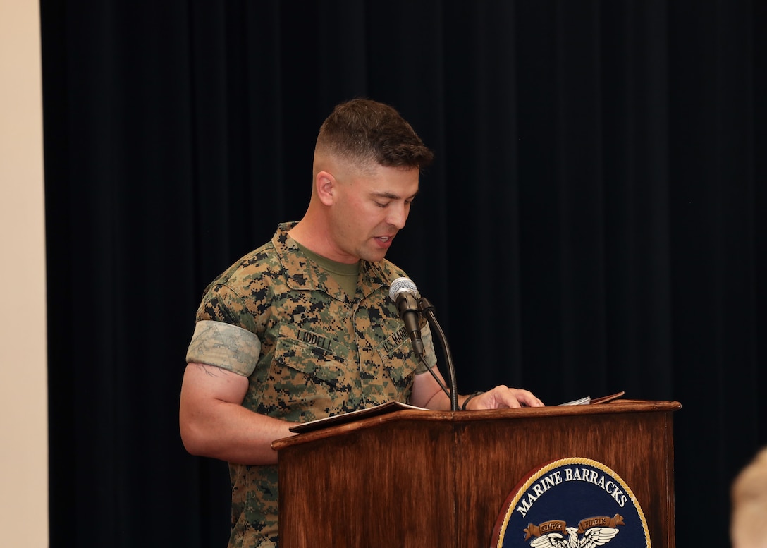 U.S. Marine Corps Sgt. Alex Liddell, narrator with the Drum and Bugle Corps, speaks during the Headquarters and Service Company change of command ceremony at Marine Barracks Washington, Washington, D.C., May 29, 2025. Capt. Cedric Hargrove assumed command as the new Headquarters and Service Company commander after serving as the unit's motor transportation officer. (U.S. Marine Corps photo by Pfc. Brianna Davidson)