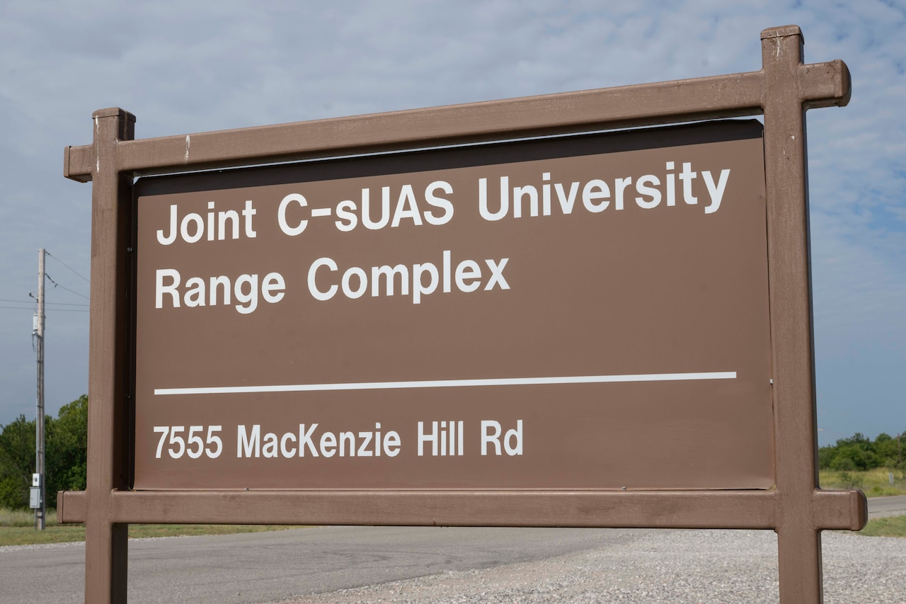 A brown sign posted beside a road reads, "Joint C-sUAS University Range Complex."