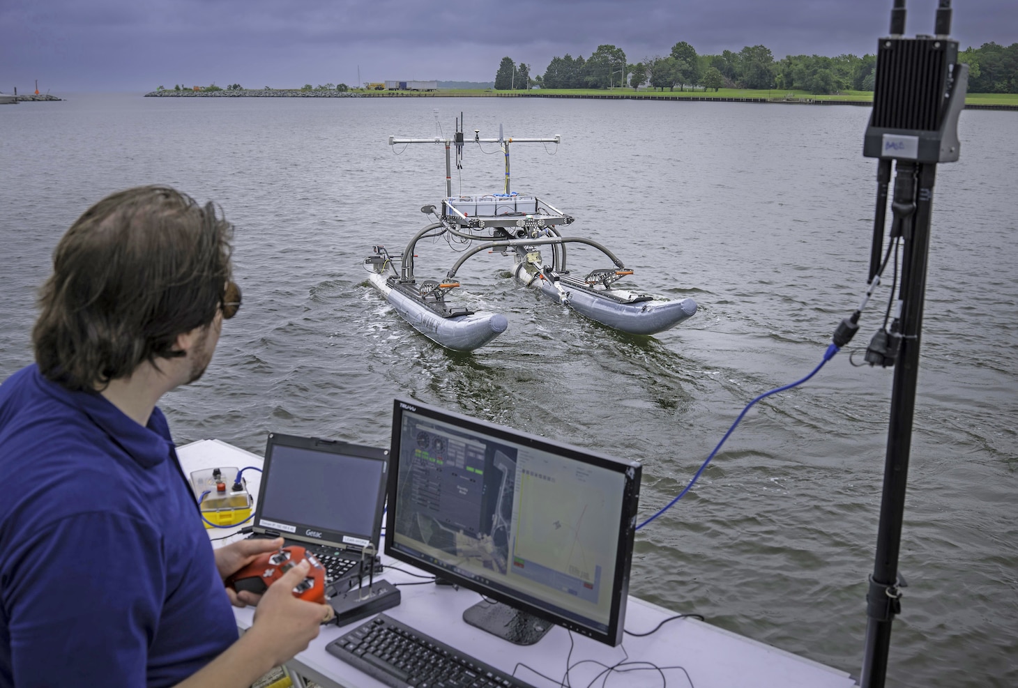 Raymond Koehler, a mechanical engineer at the Naval Air Warfare Center Aircraft Division, demonstrates unmanned swarm mission planning software at Naval Air Station Patuxent River’s West Basin Marina in Maryland on June 1. The software helps the Navy plan missions with unmanned systems by simulating drone, sensor, and arrangement combinations to achieve mission goals at sea ultimately providing warfighters faster and more effective decision making.