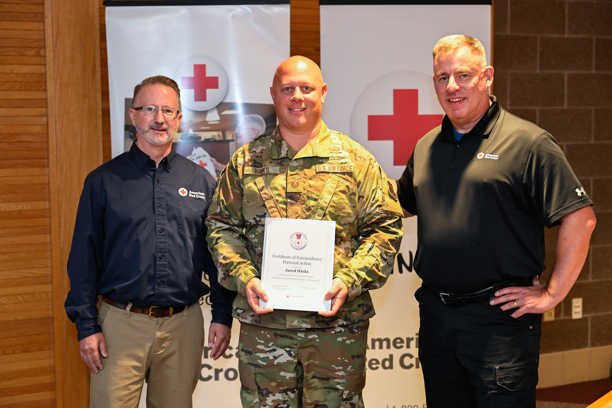 Dan Williams, Executive Director of the American Red Cross Serving Northern and Central Minnesota, Tech. Sgt. Jared Hinks, 148th Fighter Wing munitions systems specialist, and Jeff Kazel, Regional Director of the American Red Cross Service to the Armed Forces for Minnesota and the Dakotas, pose for a photo at the 148th Fighter Wing, Duluth, Minn., Sep. 22, 2025.  Tech. Sgt. Hink’s heroic actions last November resulted in sustaining a life and earning a Certificate of Extraordinary Personal Action.