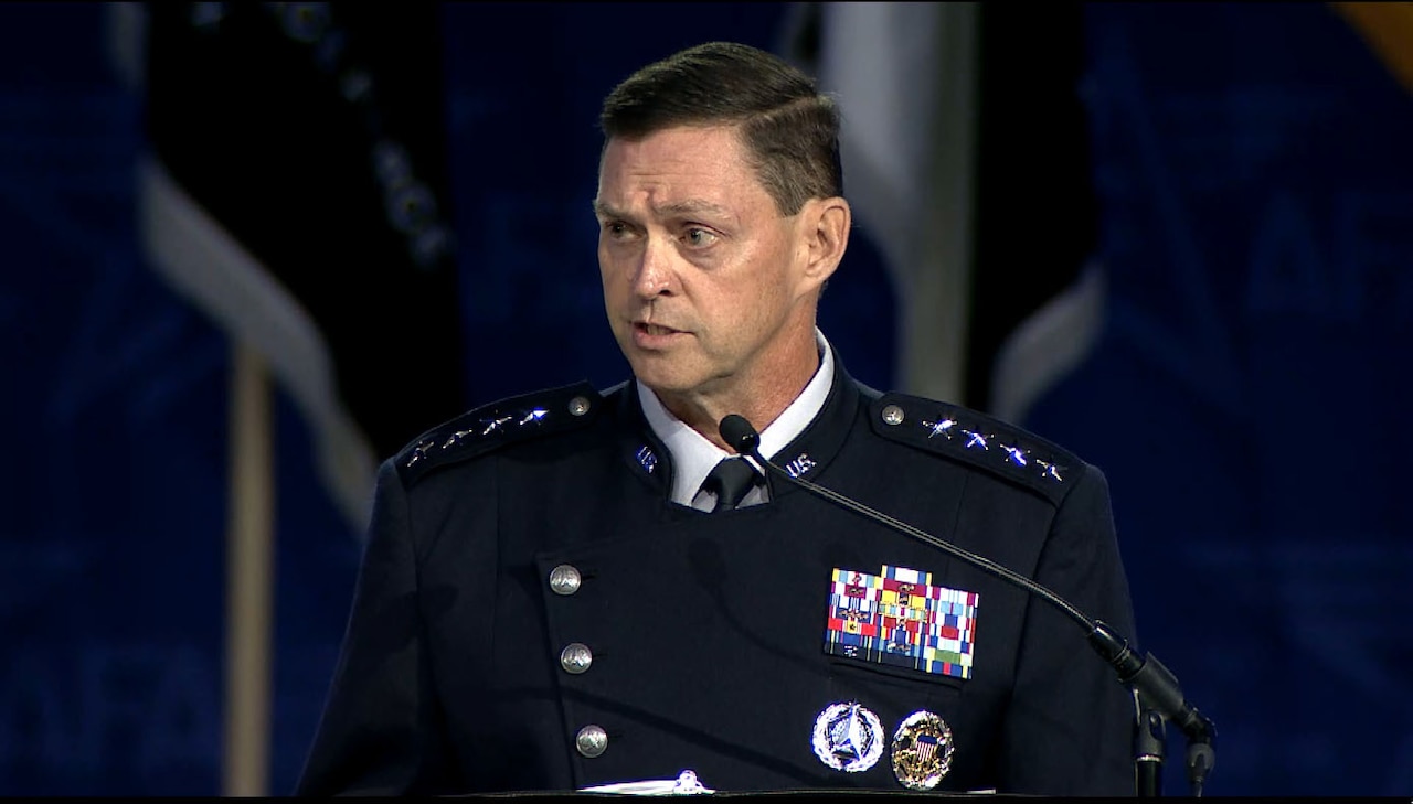 Man in a military dress uniform speaks into a microphone.