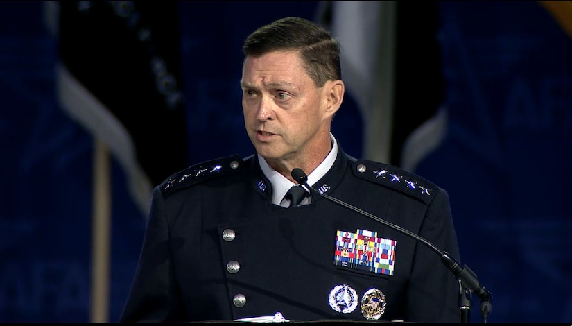 Man in a military dress uniform speaks into a microphone.