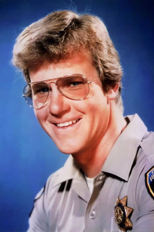 A man poses for a photo in sunglasses and a police uniform costume.