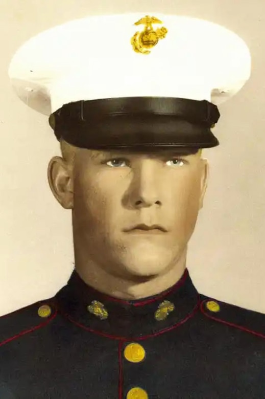 A Marine in a military dress uniform poses for a photo.