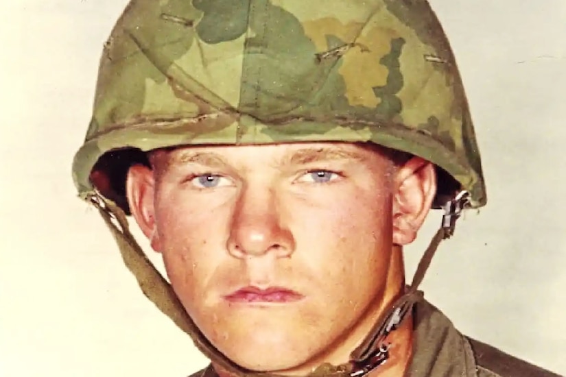 A Marine is pictured in a military uniform and helmet.