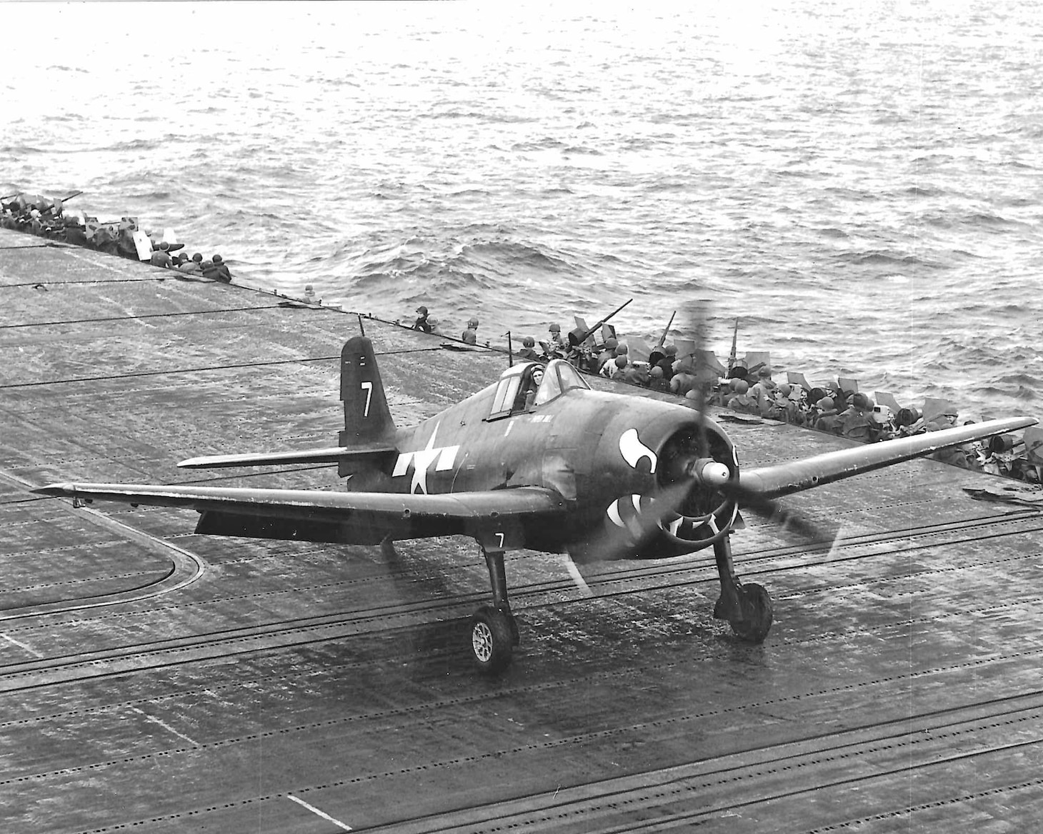 F-27’s Lt. Carl Brown, himself wounded, brings his damaged Hellcat, “Paper Doll,” onto USS Essex (CV 9). When word of the state of Brown’s home carrier was flashed around the fleet, the Essex offered to recover the ace (10.5 kills) pilot and his aircraft.