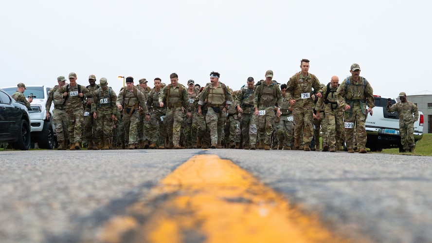 Several Airmen take off from the start line of a ruck march.