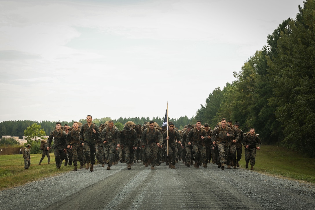 U.S. Marines with Alpha Company, Marine Barracks Washington, take off for a ruck-run during a field event at Marine Corps Base Quantico, Va., Sept. 4, 2025. The event challenged Marines to build endurance and resilience while strengthening unit cohesion outside of daily training routines. Physical training is a key part of sustaining the readiness and discipline expected of Marines at Marine Barracks Washington. (U.S. Marine Corps photo by Lance Cpl. Brynn L. Bouchard)